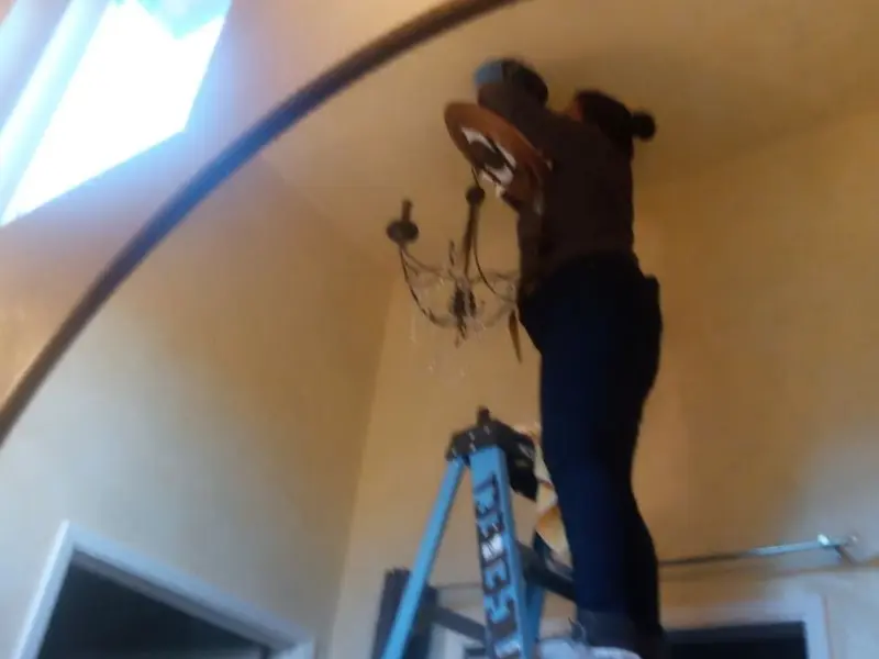 Electrician installing a chandelier in a Godley residence